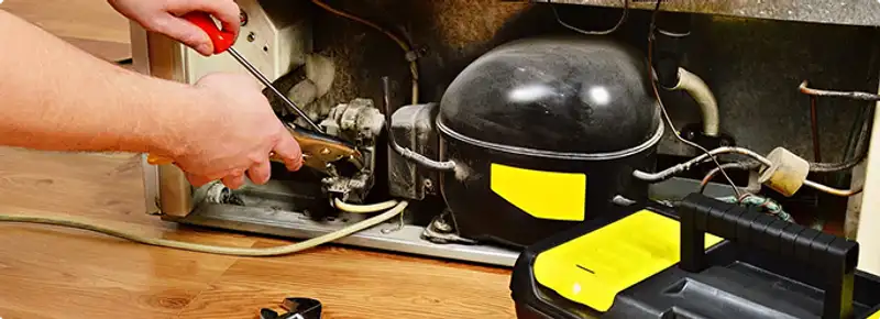 Refrigerator repair technician fixing the compressor and wiring in Manteca, CA