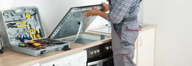Cooktop repair technician lifting a built-in stovetop for service in Stockton, CA