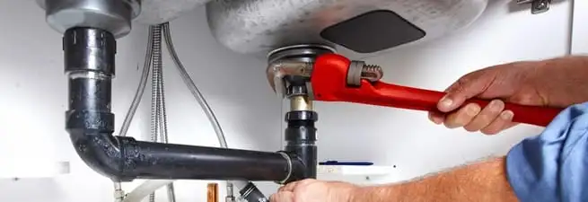 Garbage disposal repair technician tightening the sink drain and disposal connection in Stockton, CA