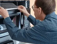 Appliance repair technician replacing a microwave vent filter in Stockton, CA