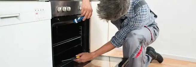 Oven repair technician inspecting and servicing an electric oven in Stockton, CA