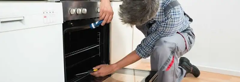 Oven repair technician inspecting and servicing an electric oven in Stockton, CA